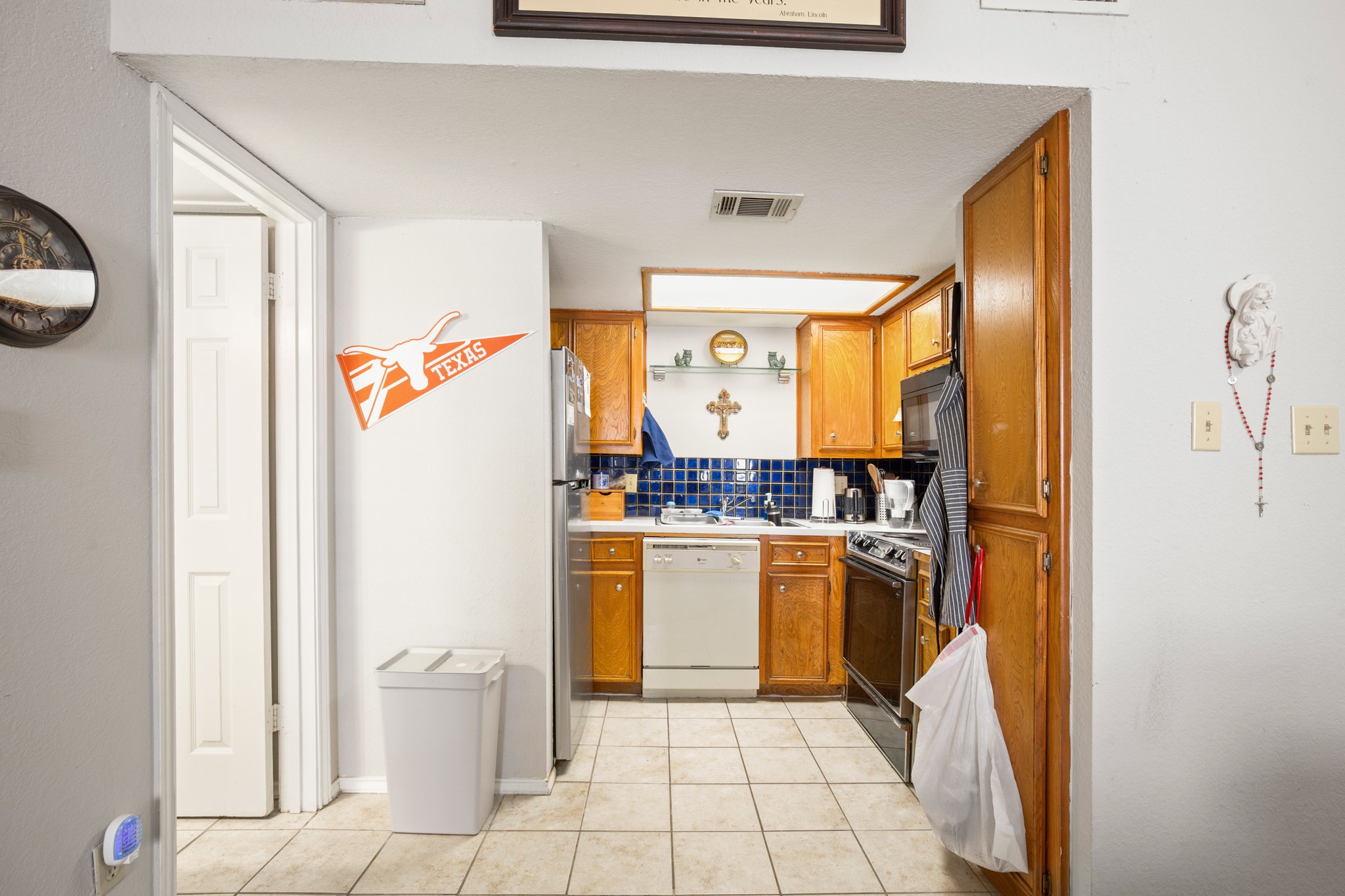 706 West 22nd Street, Unit 206 Austin, TX 78705 - Photo 5 of 18 Kitchen with wood finish cabinets, light countertops, white dishwasher, tasteful backsplash, and range with electric stovetop