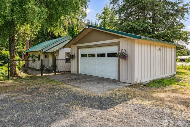 a view of a small house next to a yard with large tree