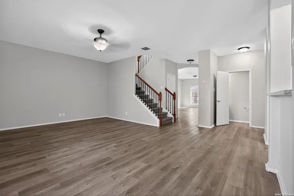 a view of an empty room with wooden floor and staircase