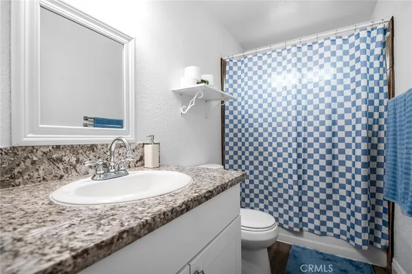 a bathroom with a granite countertop sink and a mirror with toilet