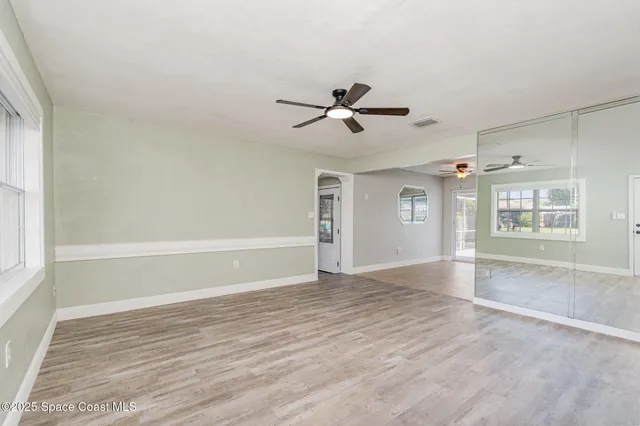 a view of empty room with wooden floor and fan