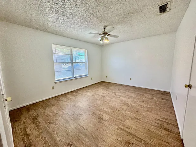 an empty room with windows and ceiling fan