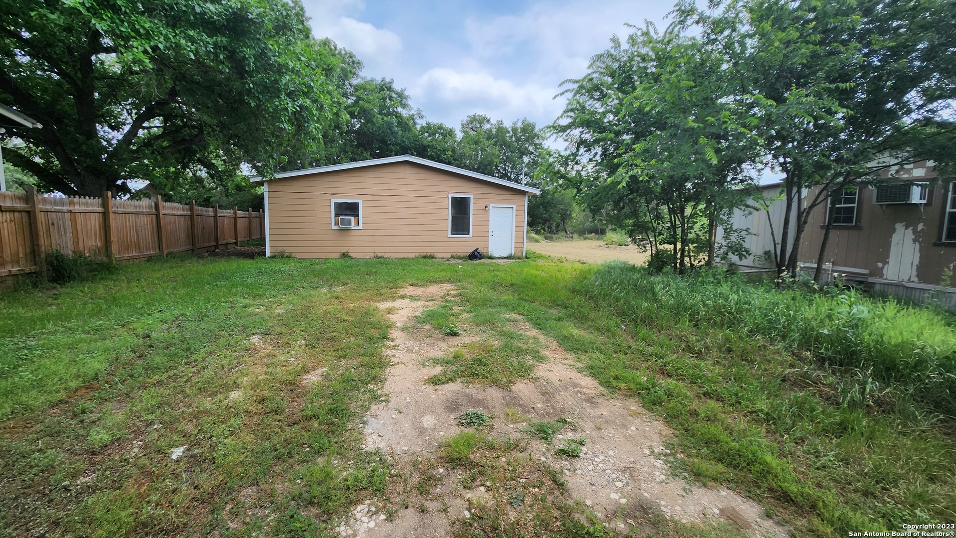 a backyard of a house with large trees and brick wall