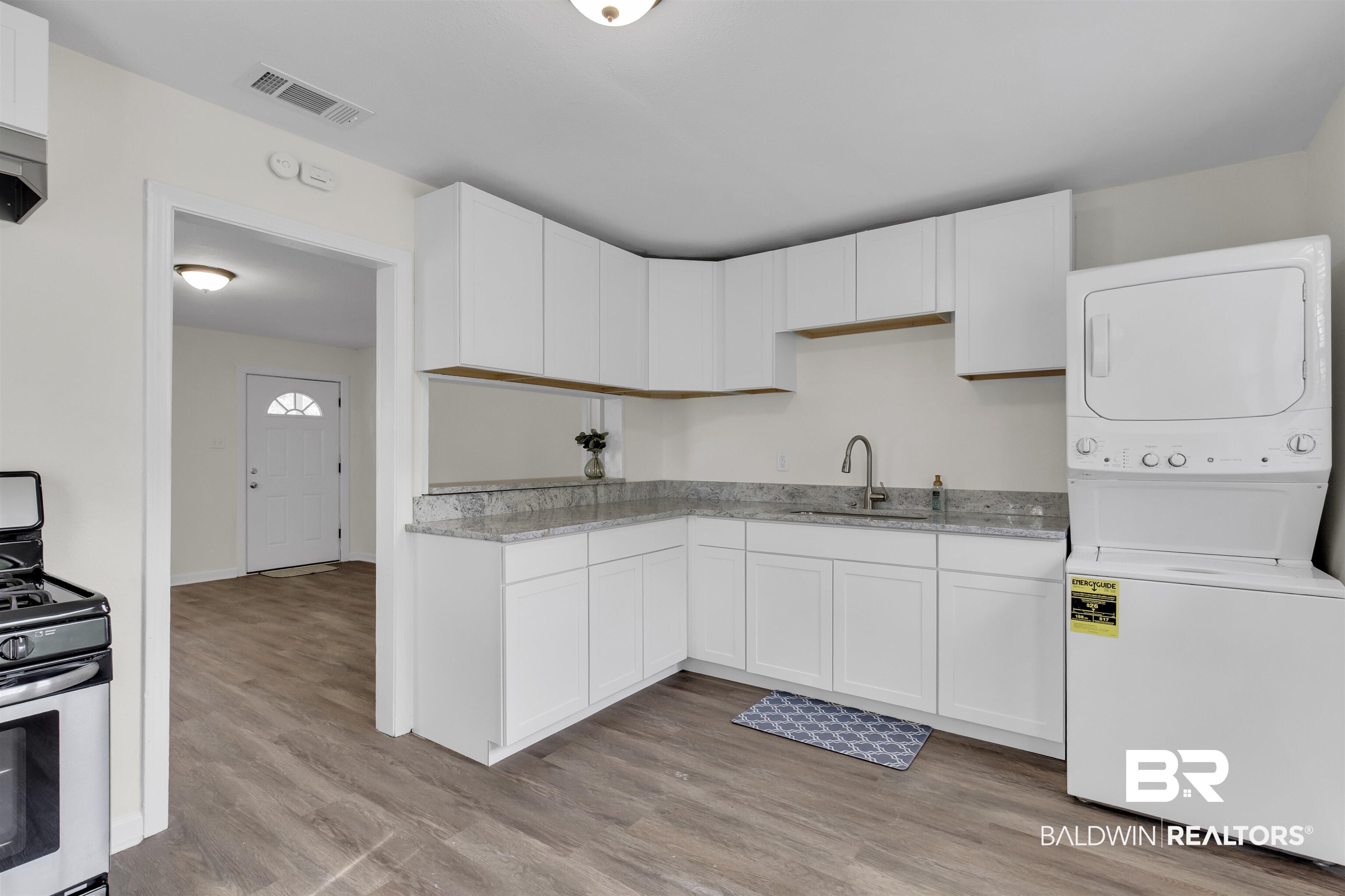 9241 Vallaris Street North Mobile, AL 36608 - Photo 13 of 17 Kitchen with stainless steel range with gas stovetop, light wood-style flooring, a sink, visible vents, and stacked washing maching and dryer