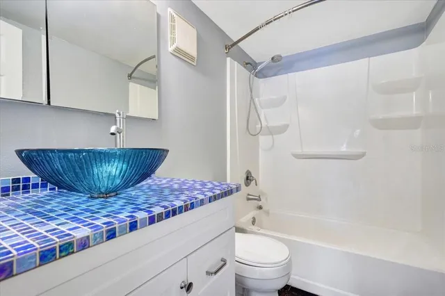 a bathroom with a granite countertop bathtub sink vanity mirror and toilet
