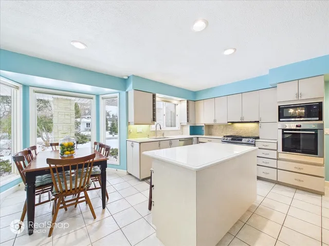 a kitchen with a dining table chairs and white appliances