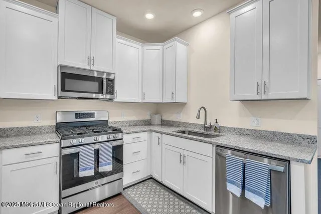 a kitchen with granite countertop white cabinets and stainless steel appliances