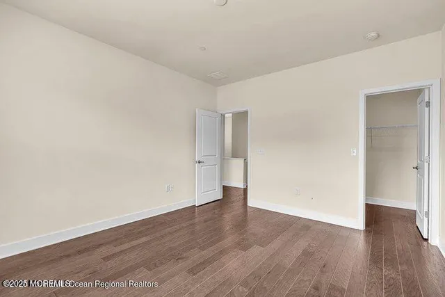 a view of an empty room with wooden floor and closet