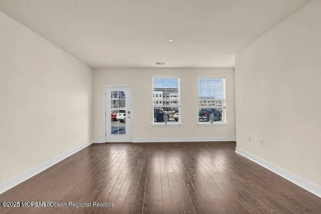an empty room with wooden floor and window