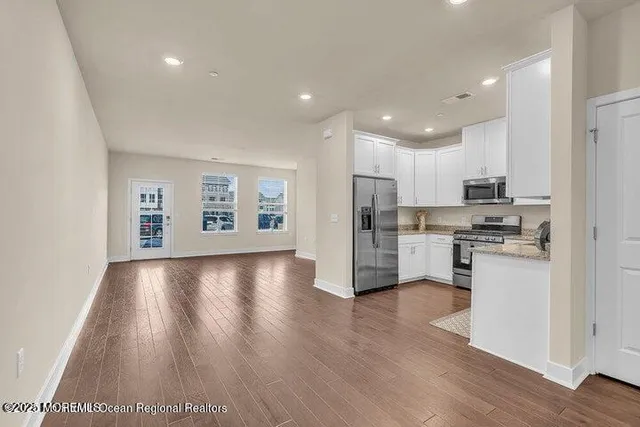 a view of kitchen with microwave a refrigerator and wooden floor