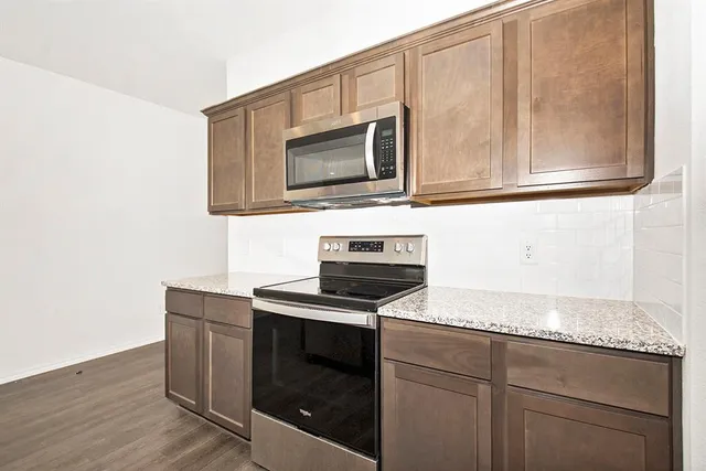 a kitchen with granite countertop cabinets stainless steel appliances and wooden floor