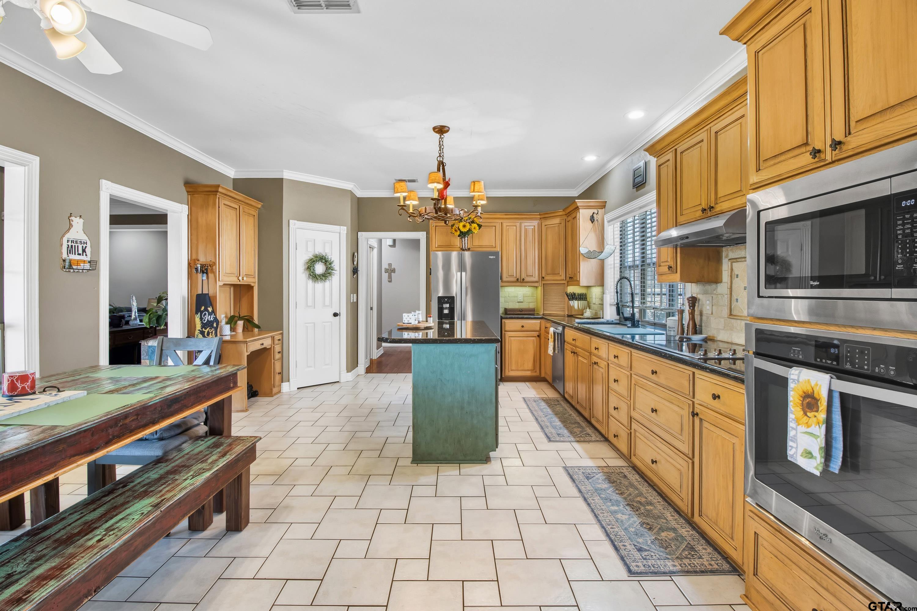 3800 Holly Ridge Drive Longview, TX 75605 - Photo 11 of 38 a large kitchen with stainless steel appliances granite countertop a stove a sink dishwasher a dining table and chairs with wooden floor