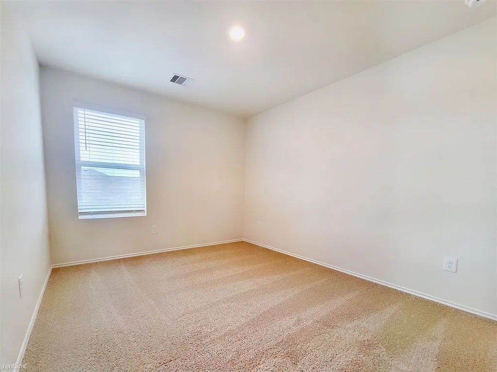 419 Sickle Loop Kyle, TX 78640 - Photo 26 of 35 A well-lit bedroom features plush carpeting and a bright window with horizontal blinds.