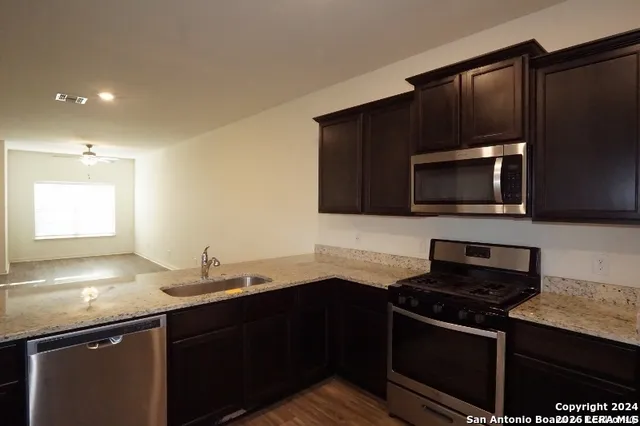 a kitchen with granite countertop a sink stove and microwave