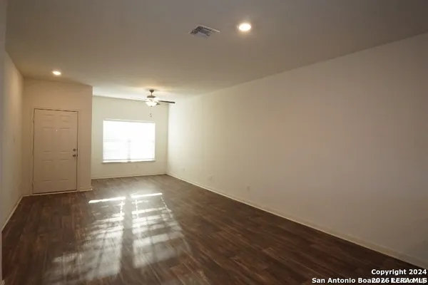 an empty room with wooden floor and windows