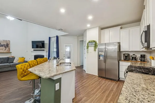 a kitchen with stainless steel appliances granite countertop a refrigerator a stove top oven a sink dishwasher and wooden floor