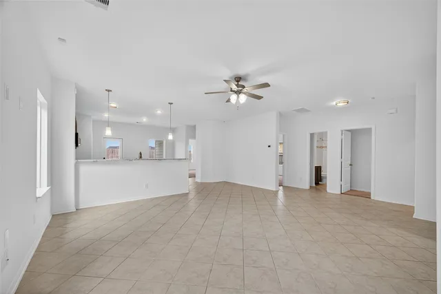 a view of an empty room with kitchen view and a window