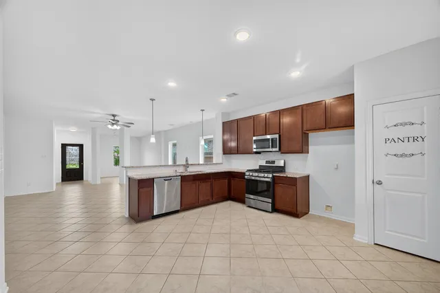 a large kitchen with a large counter top space a sink stainless steel appliances and cabinets
