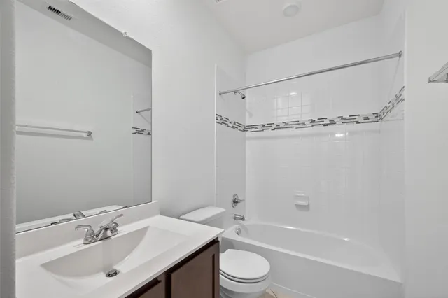 a bathroom with a bathtub shower sink vanity and toilet