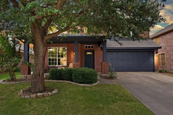 a front view of a house with a yard and tree