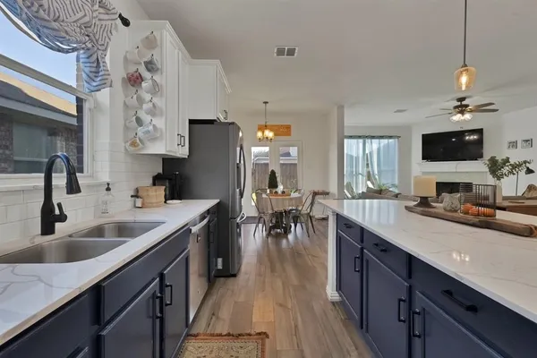 a kitchen with stainless steel appliances a table chairs refrigerator and wooden floor