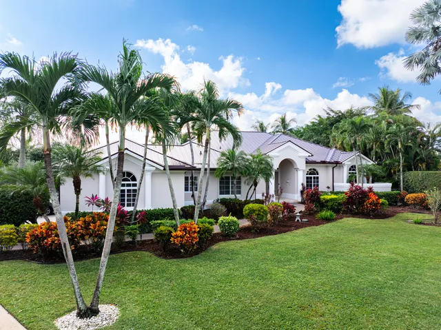 a front view of a house with garden and trees