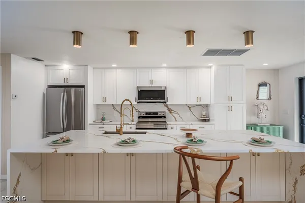a kitchen with kitchen island a stove a sink a refrigerator and a refrigerator