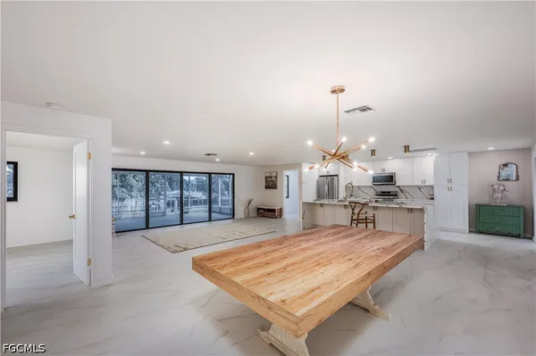 a living room with stainless steel appliances furniture a rug and kitchen view