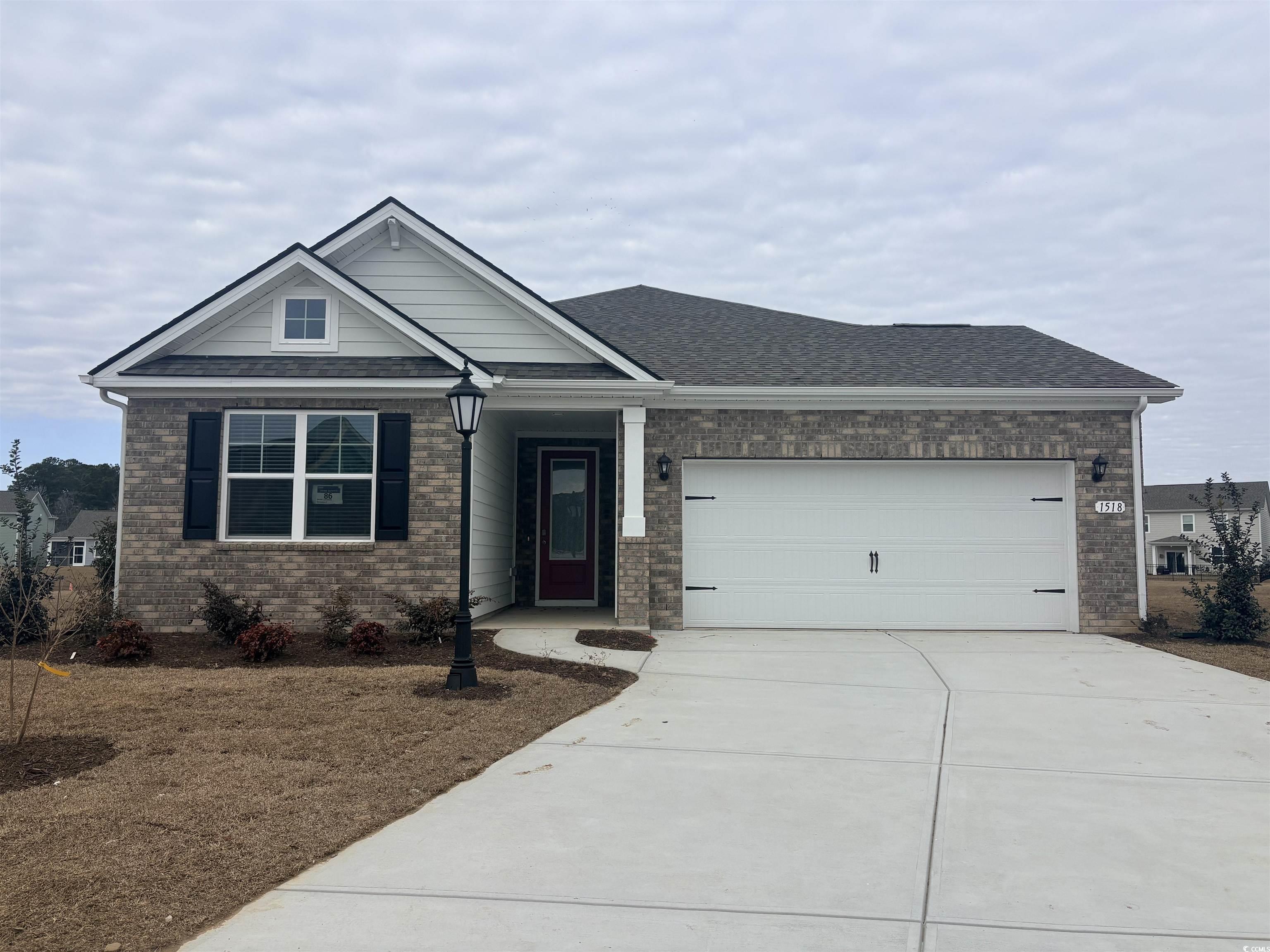 Ranch-style home with brick siding, concrete driveway, a garage, and a front lawn