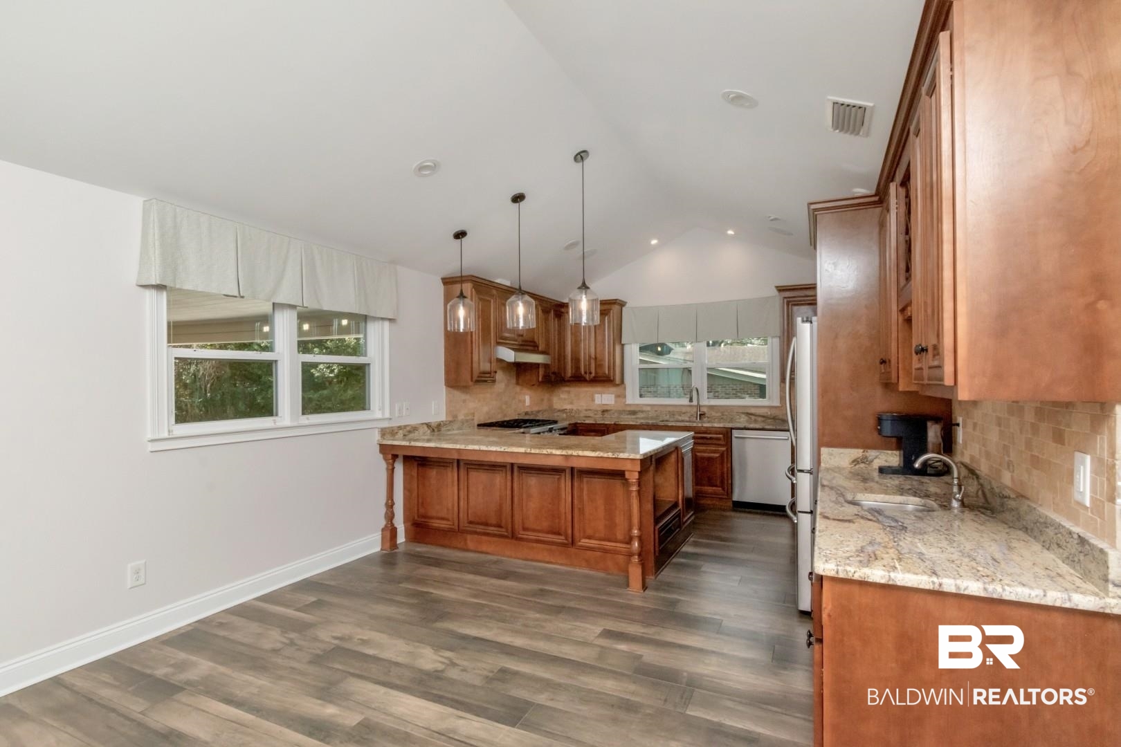 231 Rochester Road Mobile, AL 36608 - Photo 10 of 51 Kitchen with wood finish cabinetry, backsplash, vaulted ceiling, light stone countertops, and decorative light fixtures