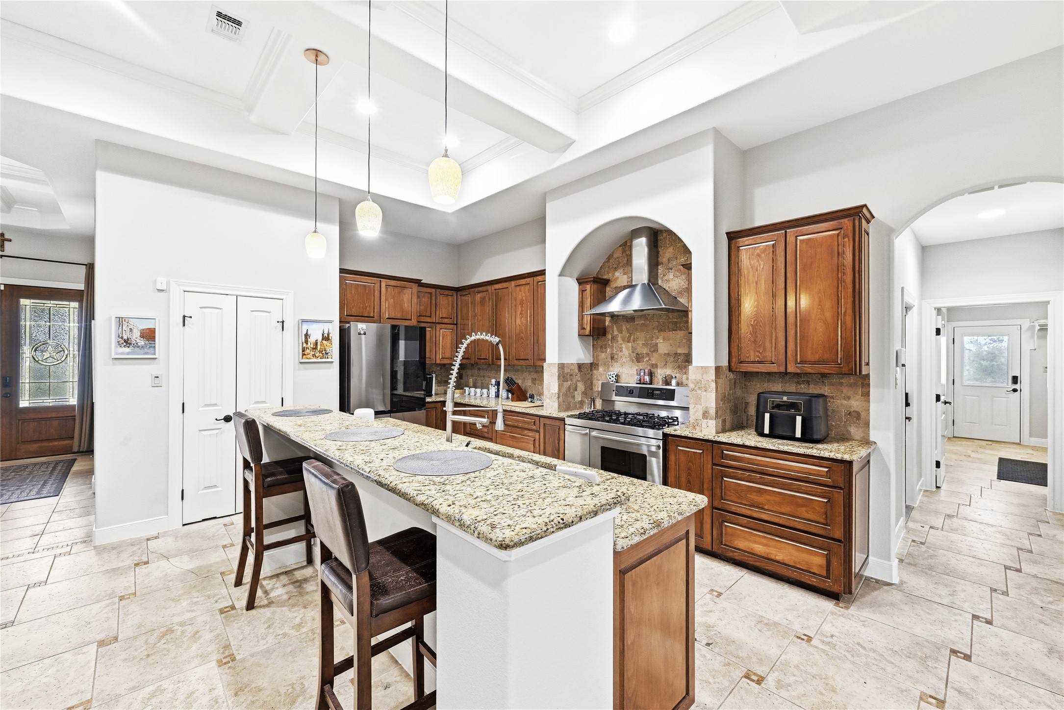 140 Winchester Road Bastrop, TX 78602 - Photo 5 of 35 Kitchen featuring arched walkways, a breakfast bar area, light stone countertops, a center island with sink, and freestanding refrigerator