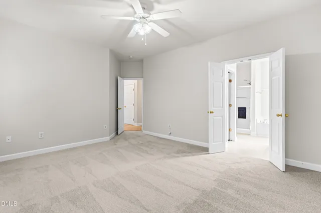 a view of an empty room and chandelier fan