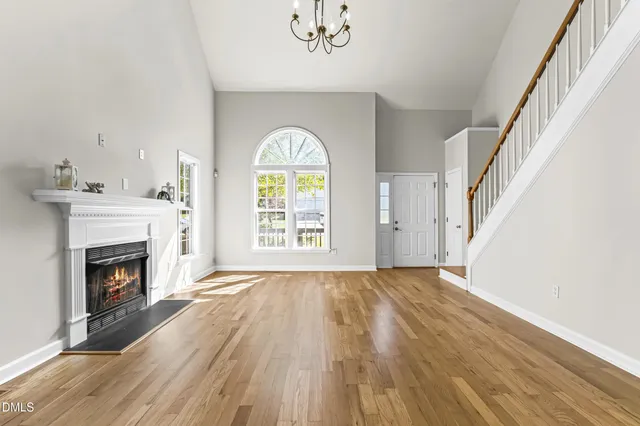 a view of an empty room with wooden floor fireplace and a window