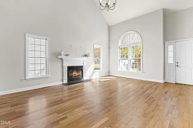 an empty room with wooden floor a fireplace and windows