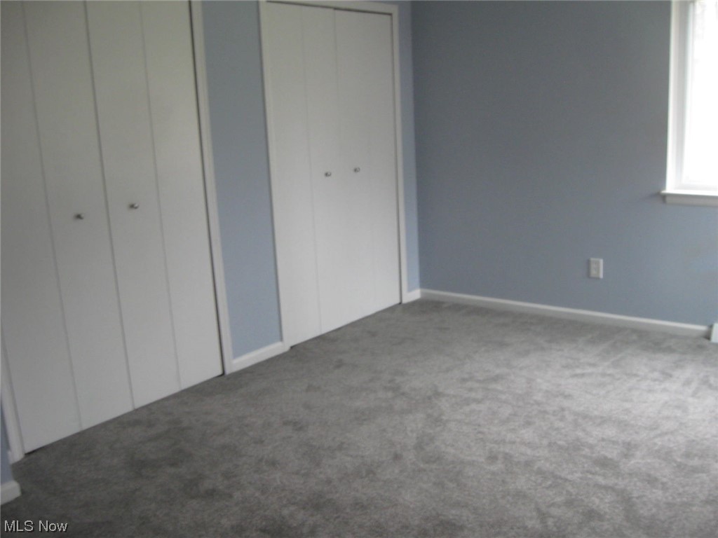 8205 Springview Road Northfield, OH 44067 - Photo 10 of 20 Unfurnished bedroom featuring dark colored carpet and multiple closets