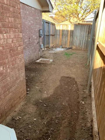 a view of a yard with wooden fence