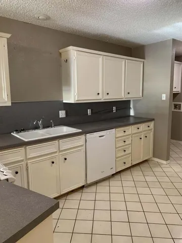 a kitchen with granite countertop white cabinets and sink