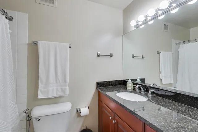 a bathroom with a granite countertop sink toilet and shower