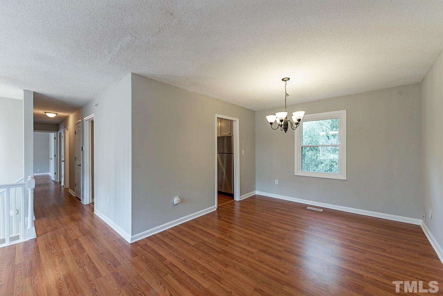 3601 Dixon Road Durham, NC 27707 - Photo 15 of 27 an empty room with wooden floor chandelier and windows