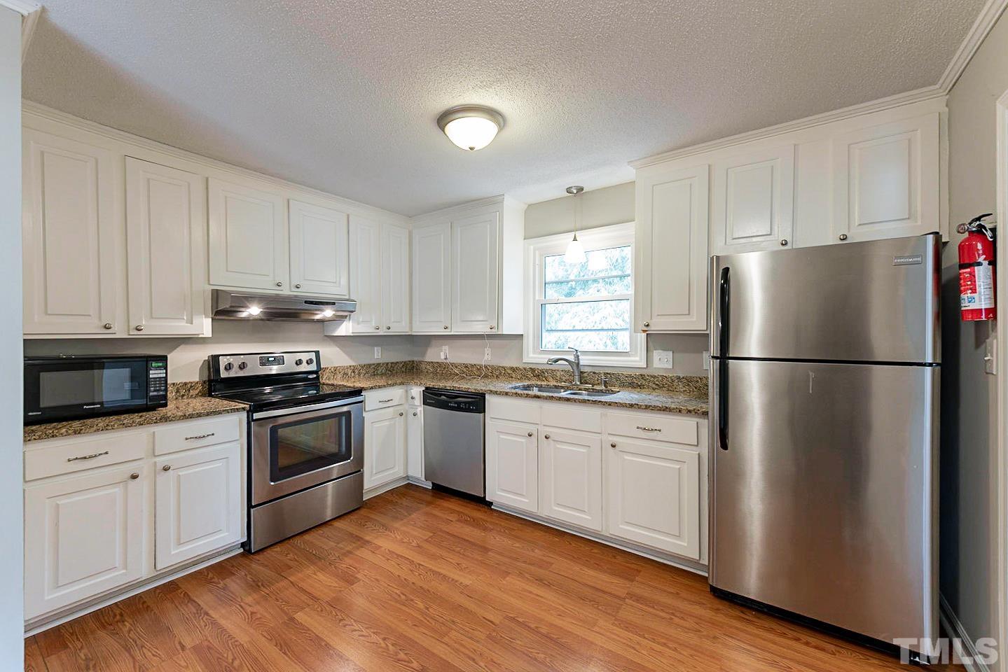 3601 Dixon Road Durham, NC 27707 - Photo 6 of 27 a kitchen with granite countertop white cabinets and white appliances