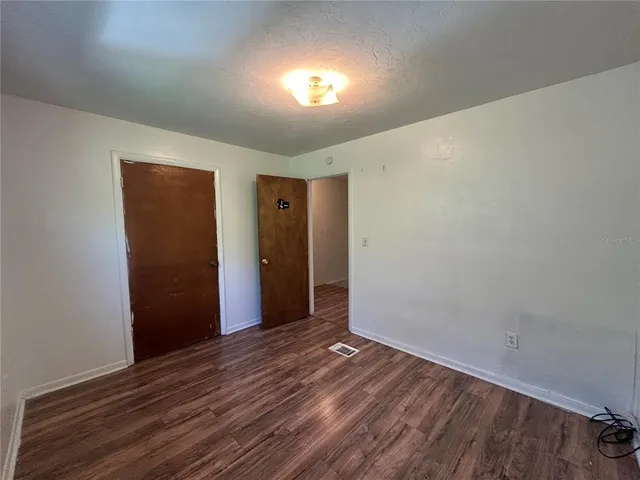 a view of an empty room with wooden floor and window
