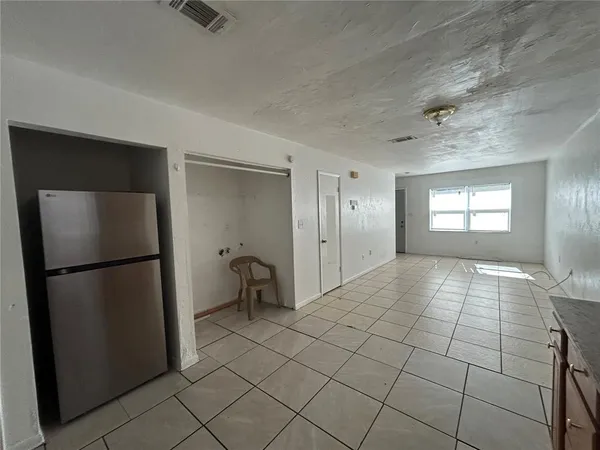 a view of a refrigerator in kitchen and an empty room