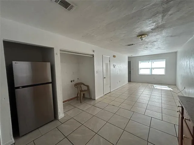 a view of a refrigerator in kitchen and an empty room