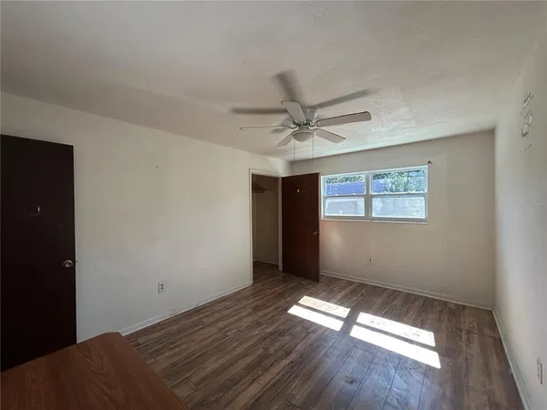 a view of empty room with wooden floor and fan
