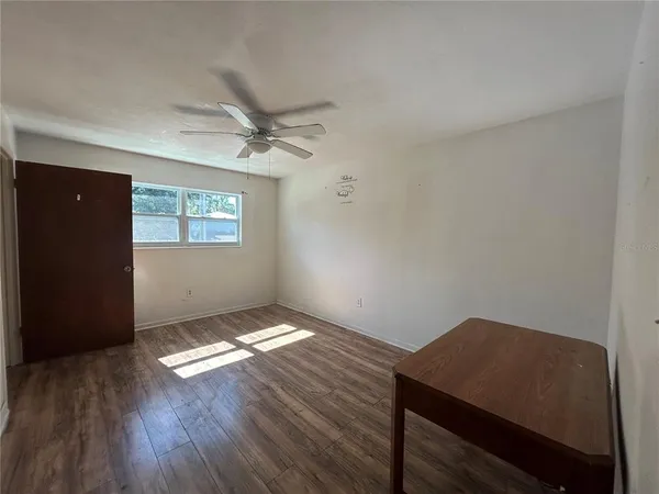 a view of an empty room with a window and wooden floor