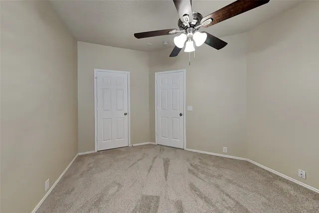an empty room with a chandelier fan and windows