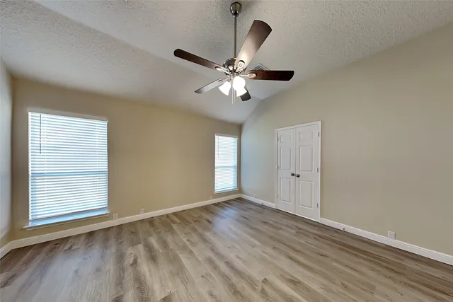 a view of an empty room with window and chandelier fan