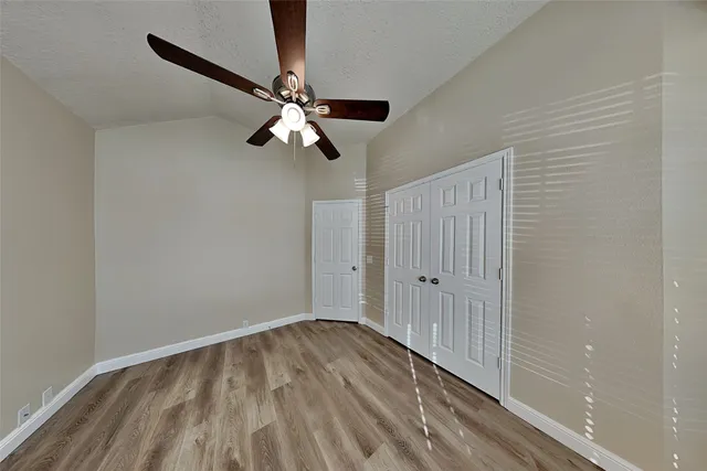 a view of empty room with wooden floor and fan