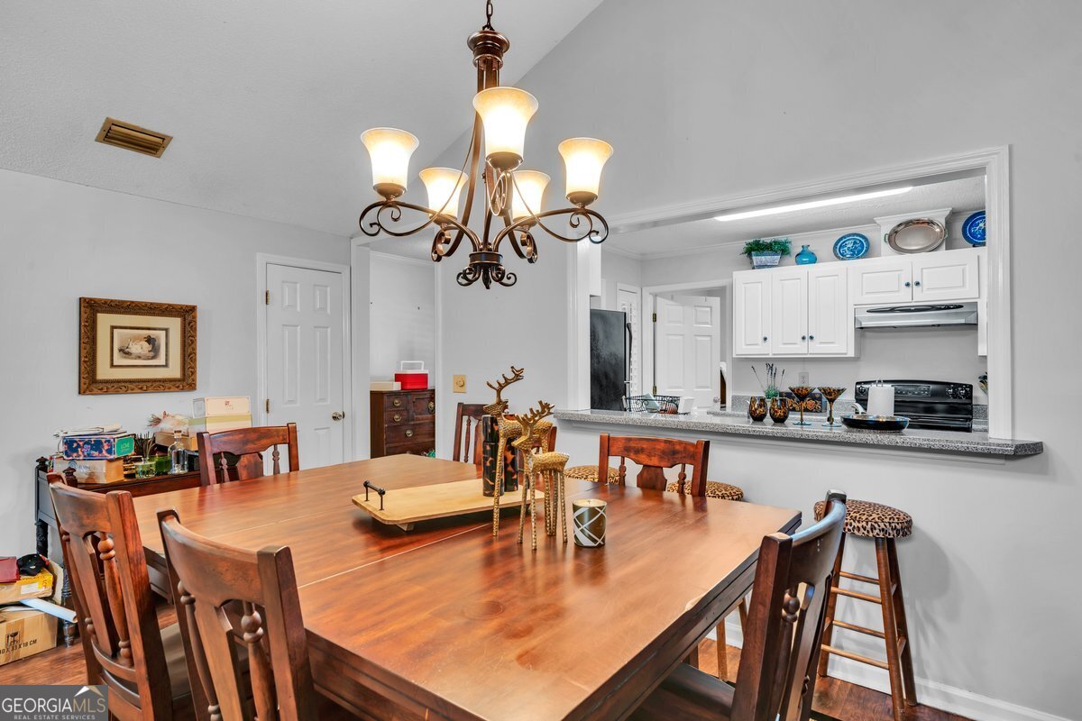 254 Valhalla Road South, Unit F Cordele, GA 31015 - Photo 11 of 41 a dining room with wooden floor a chandelier a wooden table and chairs