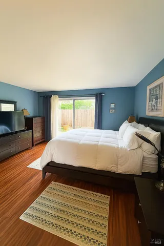 a bed sitting in a bedroom next to a window with wooden floor